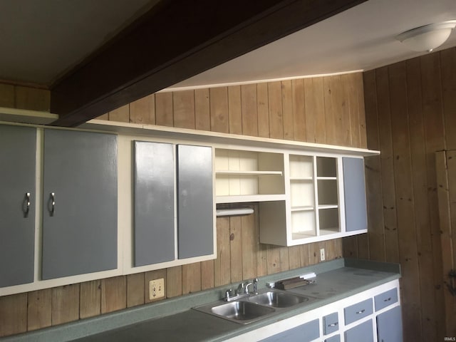 kitchen featuring beamed ceiling, sink, and wooden walls