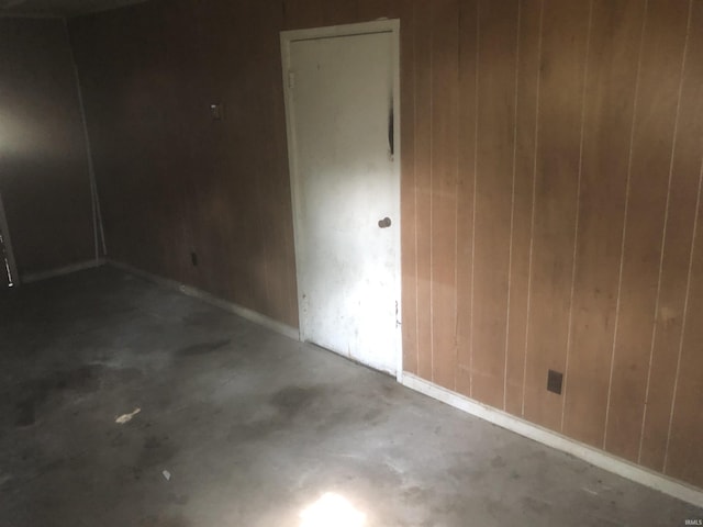 unfurnished room featuring wooden walls and concrete flooring