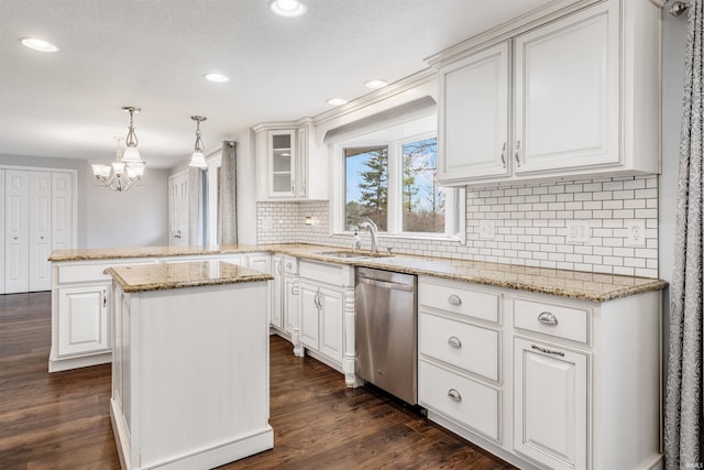 kitchen featuring dishwasher, sink, hanging light fixtures, dark hardwood / wood-style floors, and a kitchen island