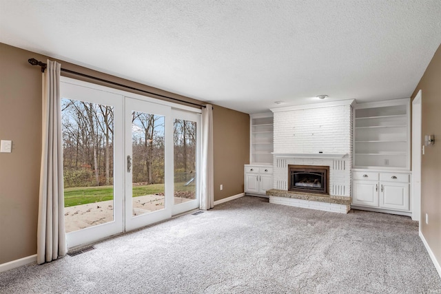 unfurnished living room featuring carpet floors, a textured ceiling, and a brick fireplace