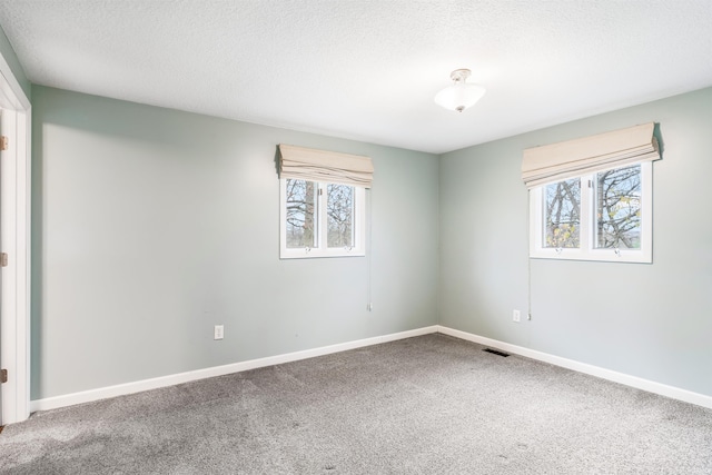 carpeted empty room featuring a textured ceiling