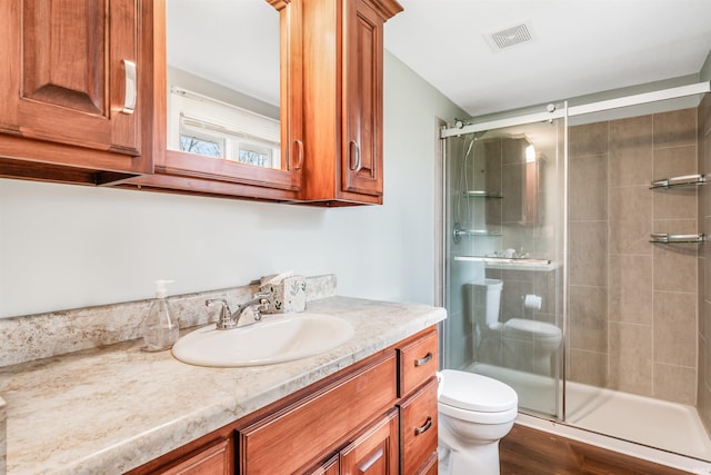 bathroom featuring hardwood / wood-style floors, vanity, toilet, and an enclosed shower