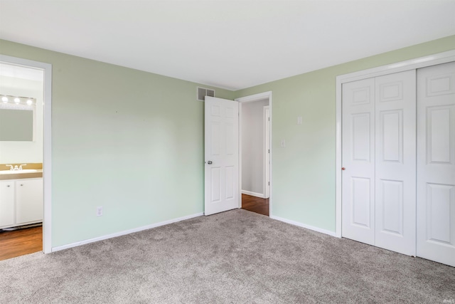 unfurnished bedroom featuring carpet flooring, connected bathroom, a closet, and sink