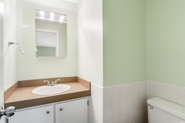 bathroom with vanity, tile walls, and toilet