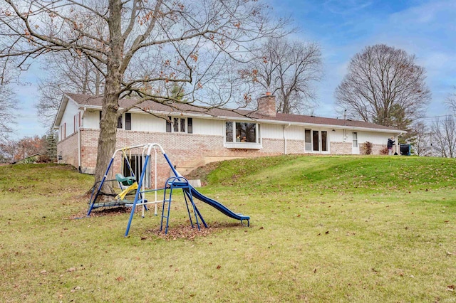 rear view of house featuring a playground and a lawn