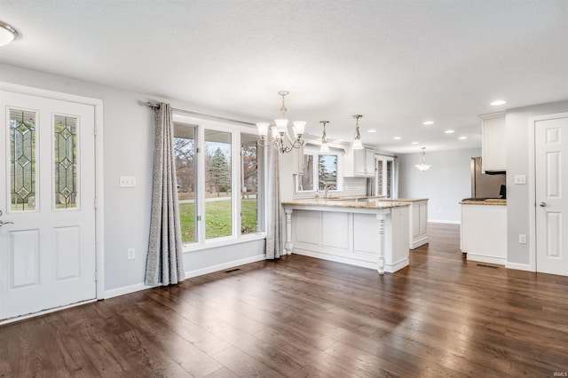 kitchen with kitchen peninsula, dark hardwood / wood-style flooring, white cabinets, and hanging light fixtures