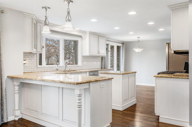 kitchen featuring kitchen peninsula, dark hardwood / wood-style floors, white cabinetry, and hanging light fixtures