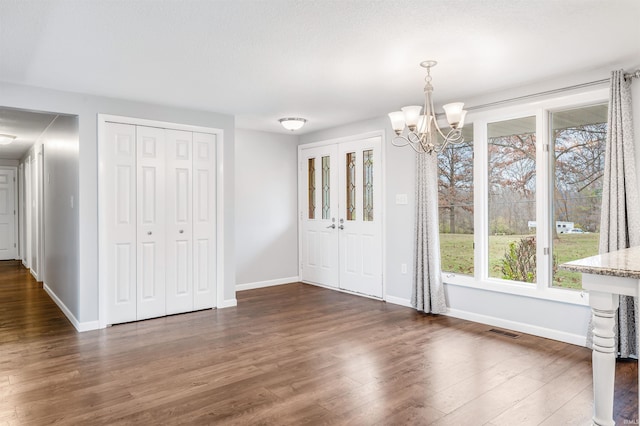 unfurnished dining area with a chandelier, plenty of natural light, and dark wood-type flooring