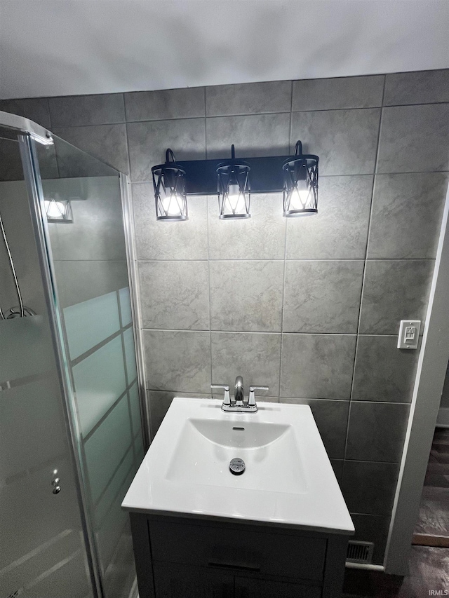 bathroom featuring vanity, tile walls, and walk in shower