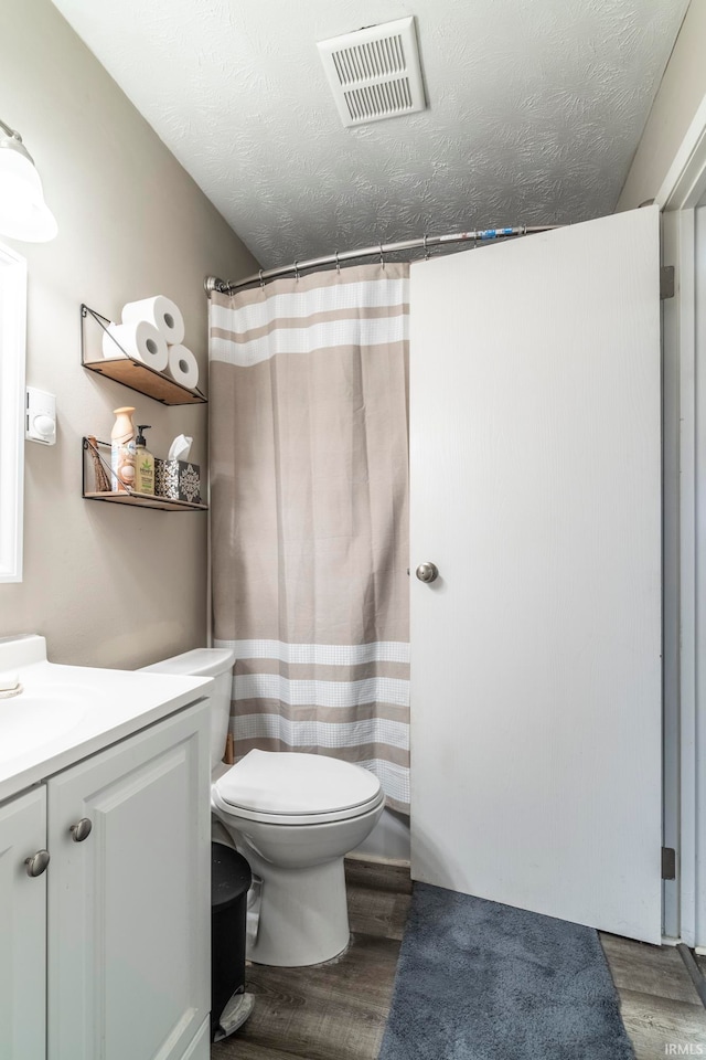 bathroom featuring vanity, a textured ceiling, hardwood / wood-style flooring, and toilet