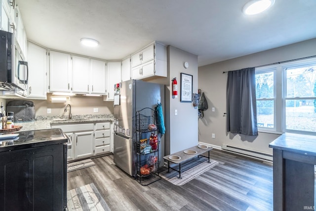 kitchen featuring appliances with stainless steel finishes, baseboard heating, sink, dark hardwood / wood-style floors, and white cabinetry