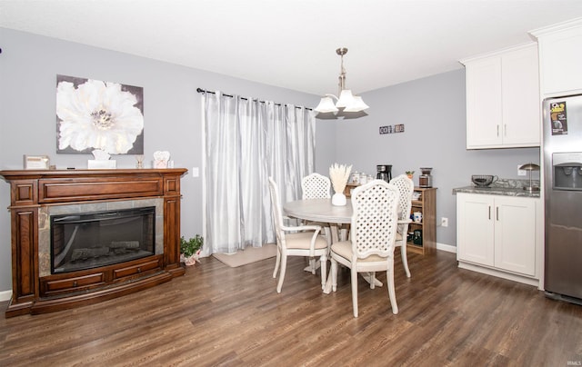 dining space featuring dark hardwood / wood-style floors, an inviting chandelier, and a tiled fireplace