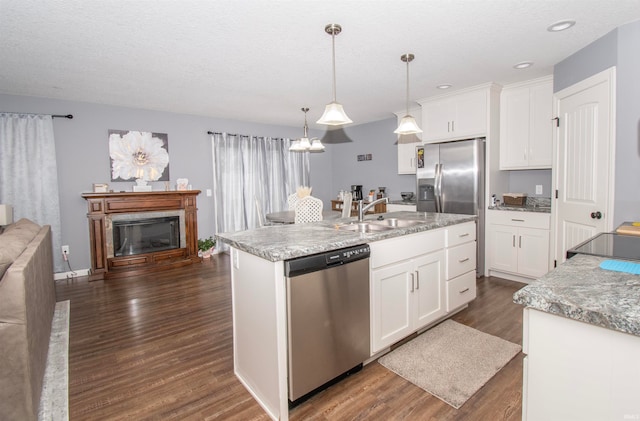 kitchen featuring pendant lighting, dark wood-type flooring, sink, appliances with stainless steel finishes, and white cabinetry