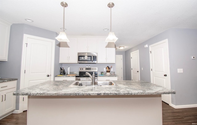 kitchen with appliances with stainless steel finishes, a center island with sink, hanging light fixtures, and dark hardwood / wood-style floors