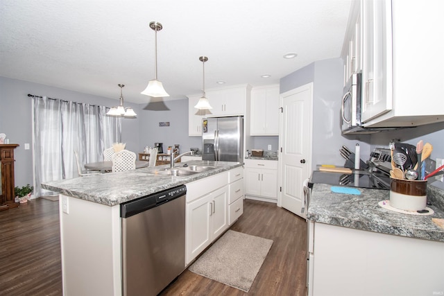 kitchen featuring an island with sink, decorative light fixtures, dark hardwood / wood-style flooring, white cabinetry, and stainless steel appliances