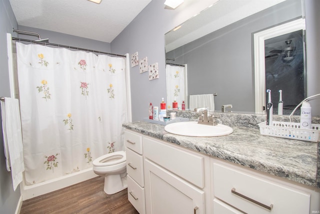 bathroom with a shower with curtain, hardwood / wood-style floors, a textured ceiling, toilet, and vanity