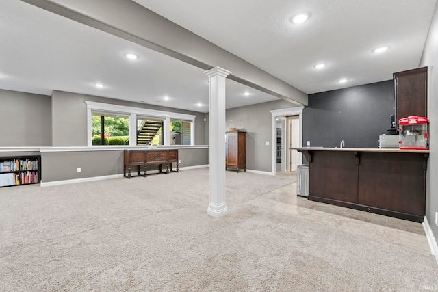 interior space featuring kitchen peninsula, dark brown cabinetry, a breakfast bar, and light colored carpet