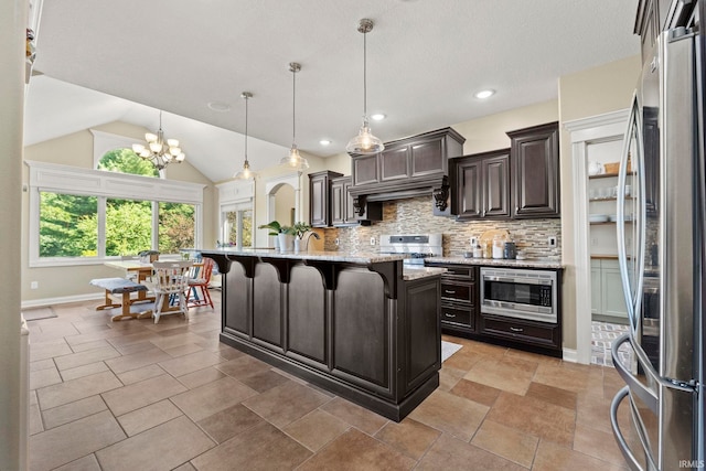 kitchen featuring a kitchen bar, appliances with stainless steel finishes, tasteful backsplash, vaulted ceiling, and a center island with sink