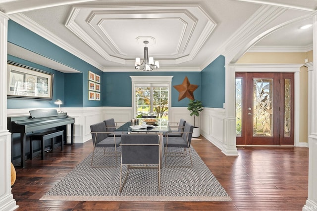 dining space with dark hardwood / wood-style flooring, a tray ceiling, an inviting chandelier, and ornamental molding