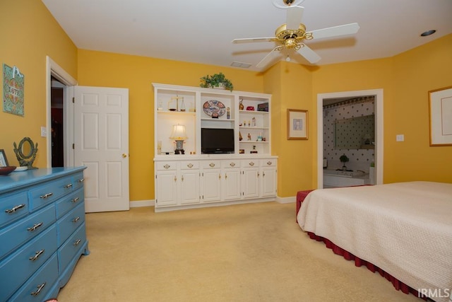 bedroom featuring light colored carpet, ceiling fan, and ensuite bathroom