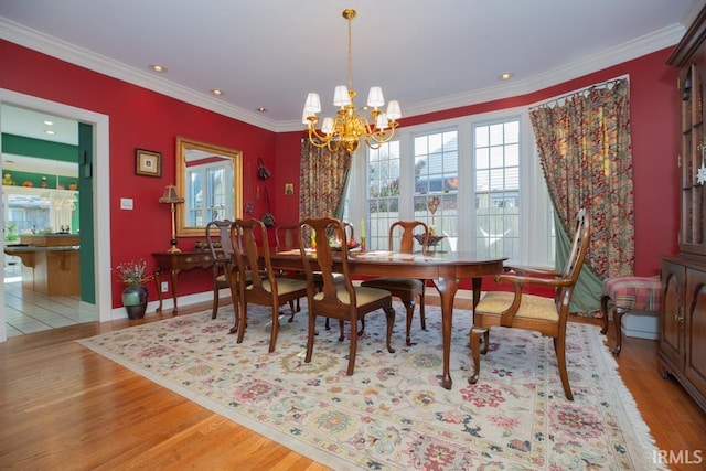 dining area with crown molding, light hardwood / wood-style floors, and an inviting chandelier