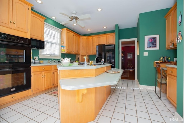 kitchen with a kitchen breakfast bar, ceiling fan, black appliances, a kitchen island, and light tile patterned flooring