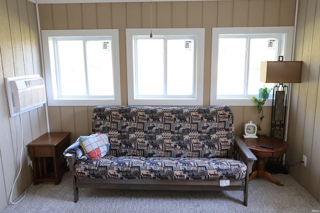 sitting room featuring a wall mounted air conditioner, carpet floors, and a wealth of natural light