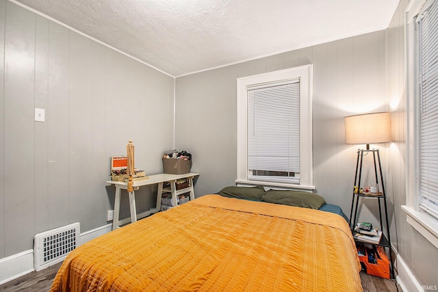 bedroom featuring crown molding, wood-type flooring, and a textured ceiling