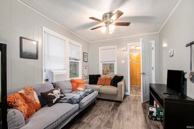 living room with a textured ceiling, hardwood / wood-style flooring, ceiling fan, and crown molding