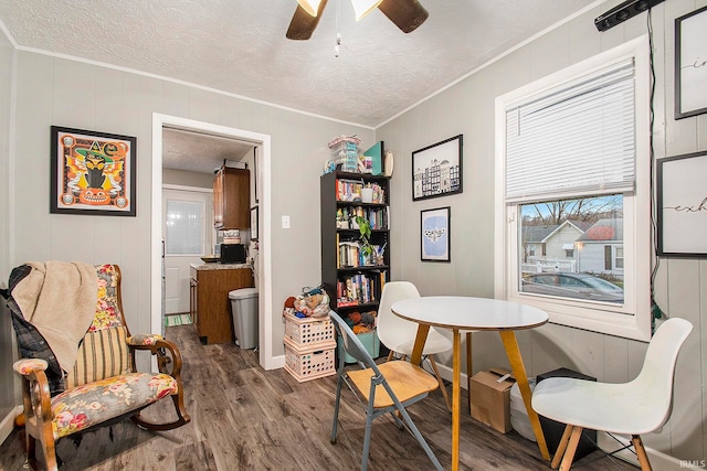 dining area with hardwood / wood-style floors, a textured ceiling, ceiling fan, and crown molding