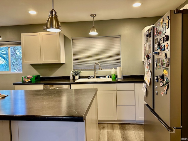 kitchen with white cabinets, appliances with stainless steel finishes, light hardwood / wood-style flooring, and sink