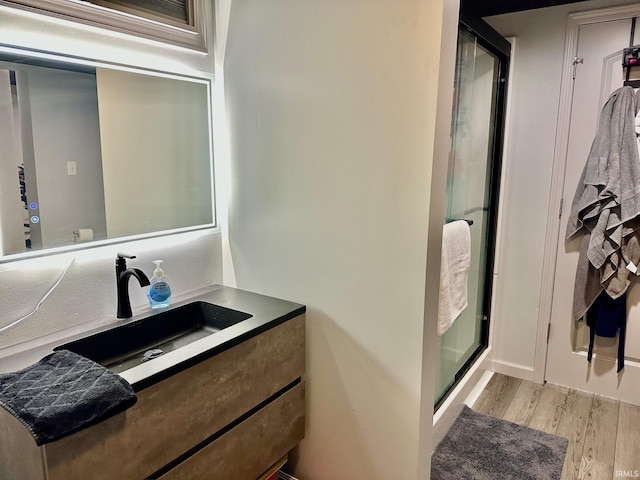 bathroom with wood-type flooring, vanity, and a shower with door