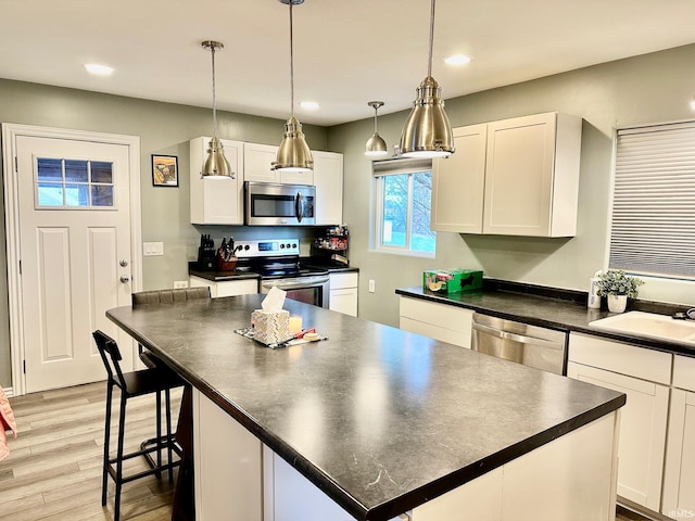 kitchen with stainless steel appliances, sink, light hardwood / wood-style flooring, white cabinets, and a center island