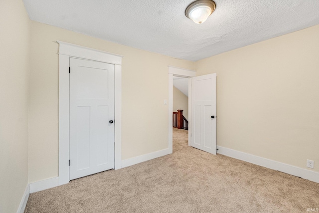 unfurnished bedroom featuring a closet, light colored carpet, and a textured ceiling