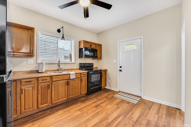 kitchen featuring ceiling fan, sink, light hardwood / wood-style flooring, decorative light fixtures, and black appliances