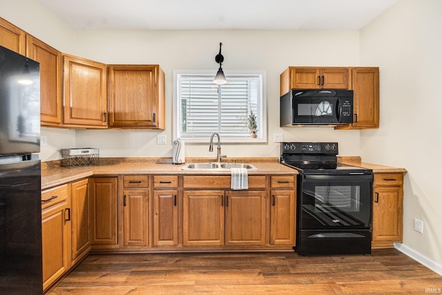 kitchen featuring black appliances, decorative light fixtures, dark hardwood / wood-style flooring, and sink