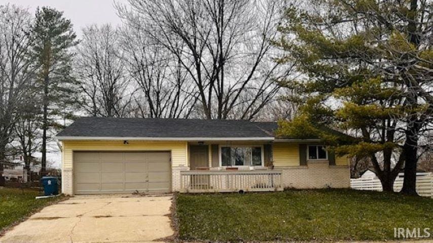 ranch-style home with a front lawn, a porch, and a garage