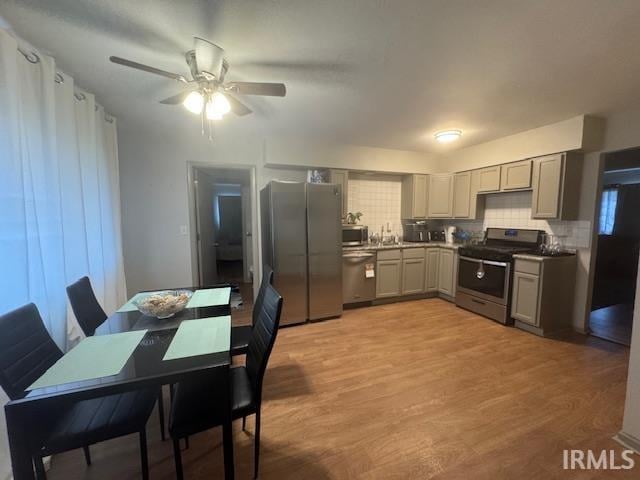 kitchen with light wood-type flooring, stainless steel appliances, gray cabinets, and tasteful backsplash