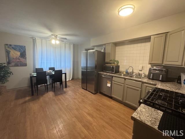 kitchen with light wood-type flooring, tasteful backsplash, stainless steel appliances, sink, and gray cabinets