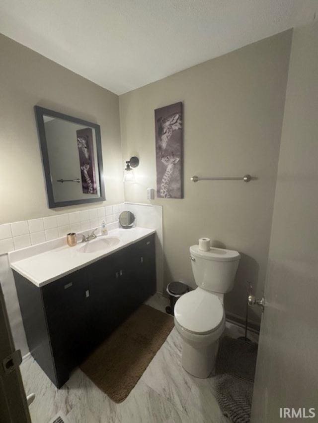 bathroom featuring tasteful backsplash, vanity, and toilet