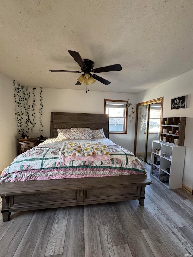 bedroom with hardwood / wood-style floors, ceiling fan, and a textured ceiling