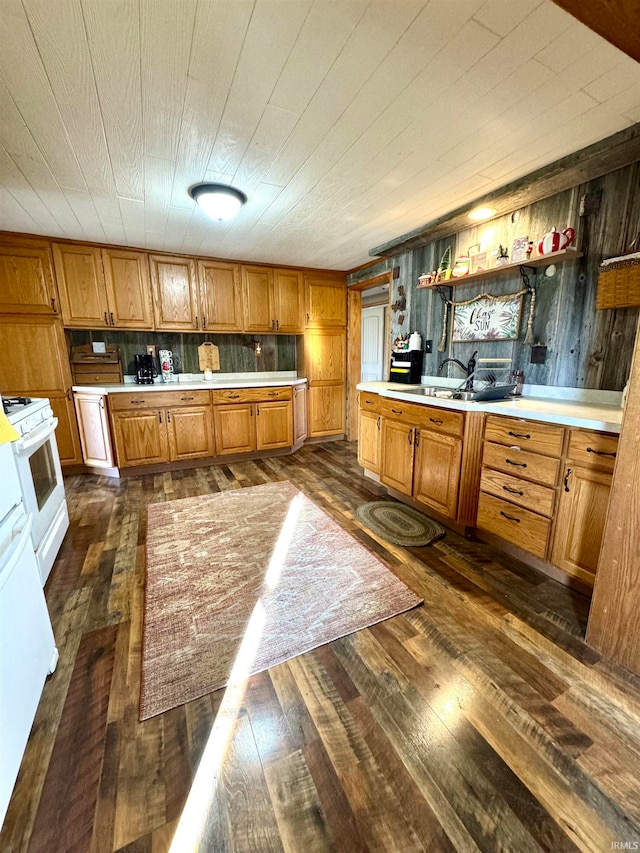 kitchen with white stove, wooden walls, dark wood-type flooring, and sink