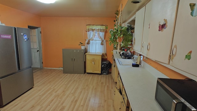 kitchen featuring sink, white cabinets, stainless steel appliances, and light wood-type flooring