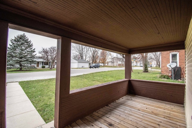 wooden deck featuring a porch and a lawn