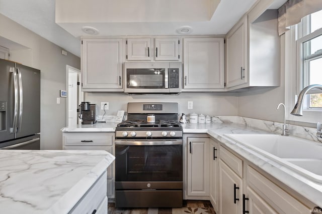 kitchen with light stone counters, white cabinetry, sink, and appliances with stainless steel finishes