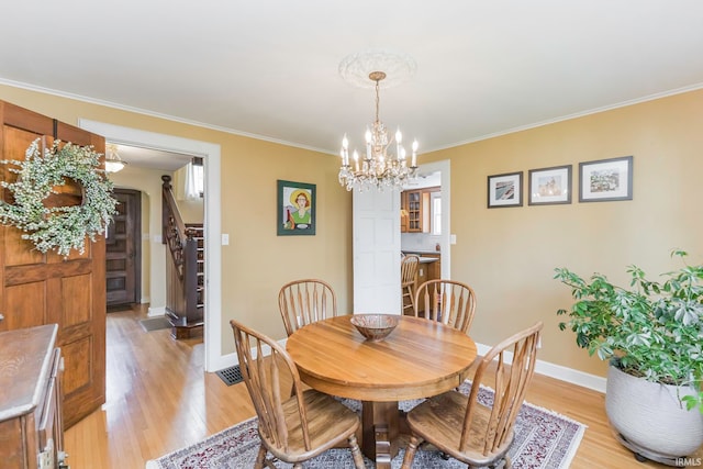 dining space featuring a notable chandelier, light wood-type flooring, and crown molding