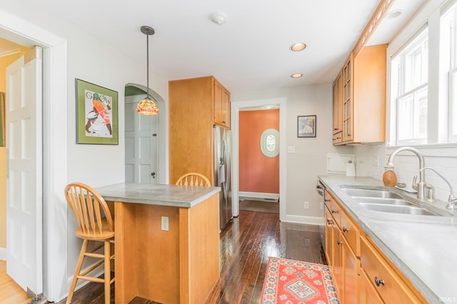 kitchen featuring appliances with stainless steel finishes, tasteful backsplash, sink, dark hardwood / wood-style floors, and hanging light fixtures