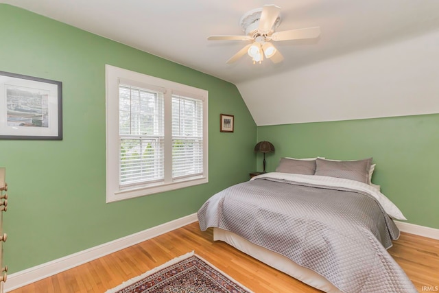 bedroom with ceiling fan, hardwood / wood-style floors, and vaulted ceiling