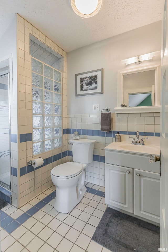 bathroom featuring tile patterned flooring, a textured ceiling, toilet, and tile walls