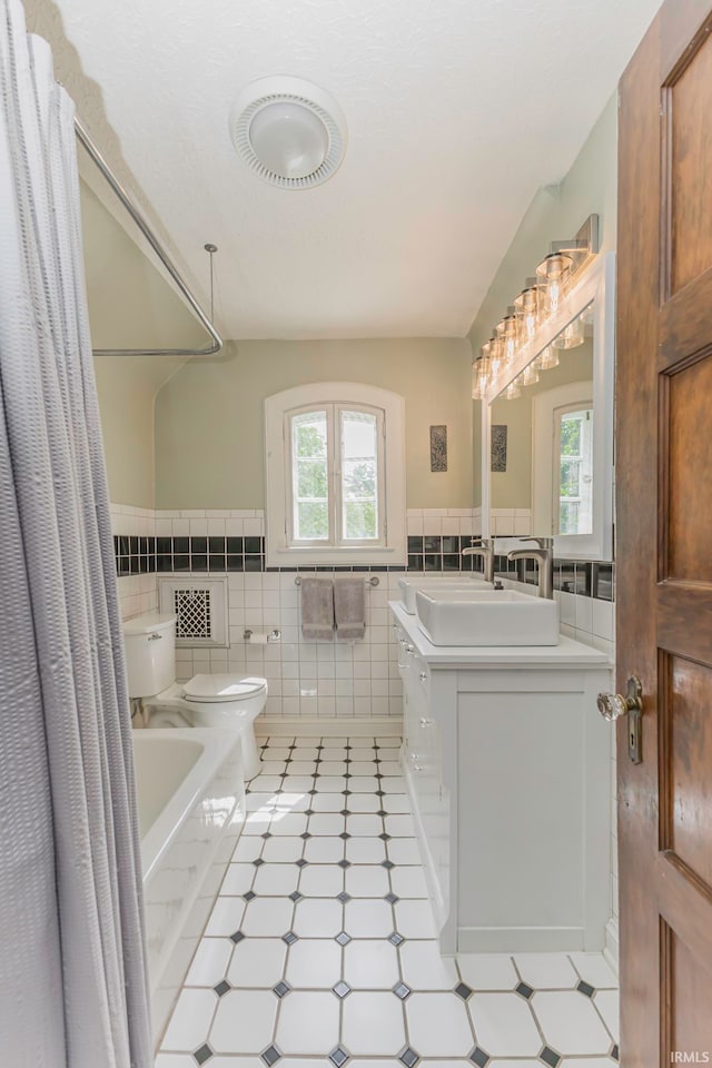 full bathroom featuring plenty of natural light, toilet, tile walls, and vanity